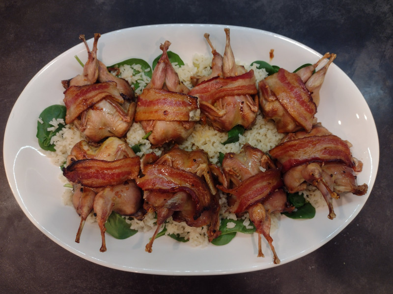 Roasted quail with bacon on rice and greens
